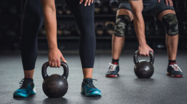 two people in gym holding kettlebells