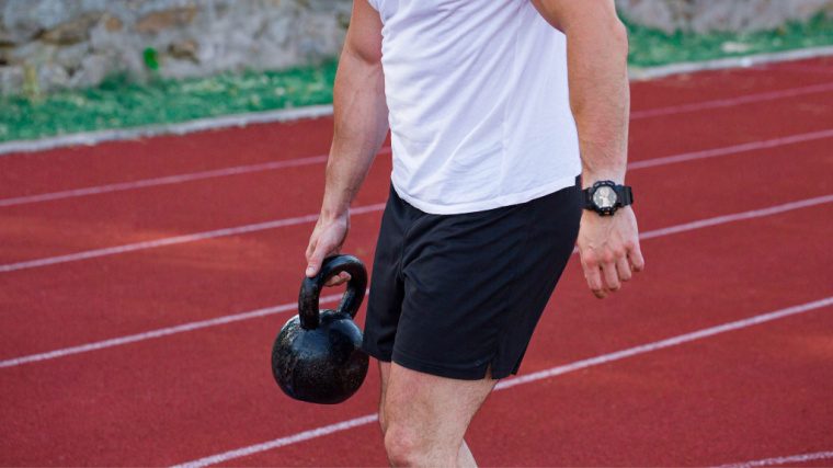 person outdoors holding kettlebell