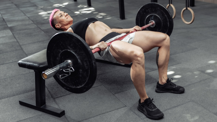 muscular person in gym doing hip thrust with barbell