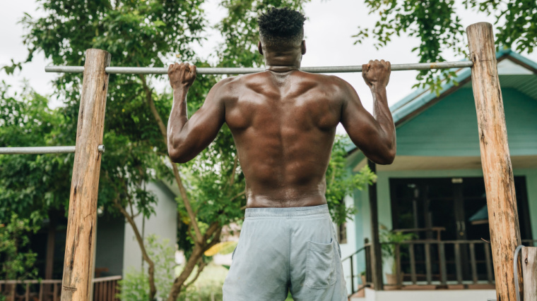 Muscular person doing pull-ups outdoors