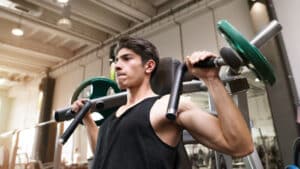 person in gym using shoulder press machine