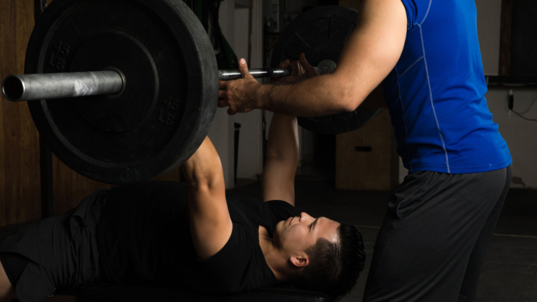 person helping lifter perform bench press