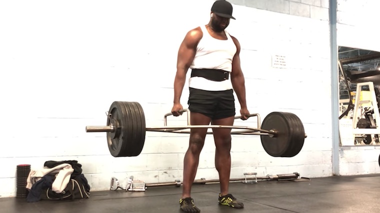 muscular person in gym doing trap bar deadlift