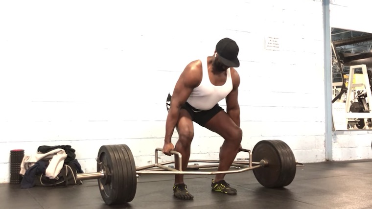 muscular person in gym preparing to deadlift trap bar