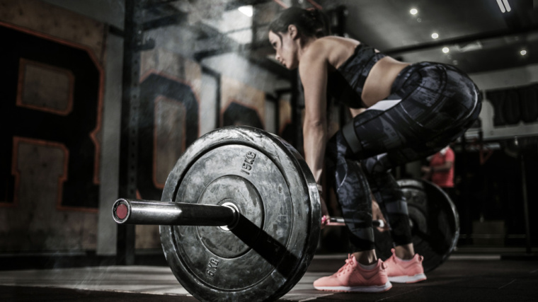 Person in gym deadlifting barbell