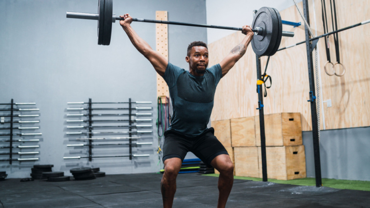 Person in gym doing barbell Olympic lift.