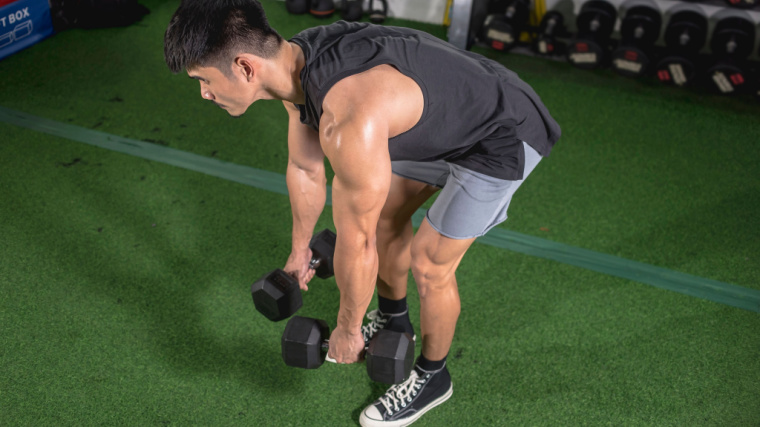 muscular person in gym doing dumbbell back exercise