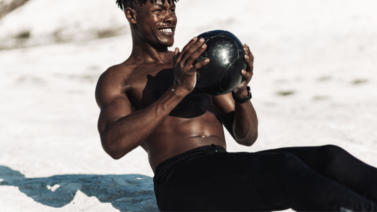Muscular person do ab exercise with medicine ball outdoors