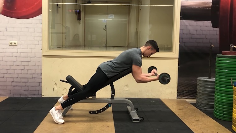 person in gym on seat curling barbell