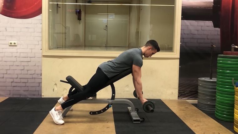 person in gym on seat curling barbell