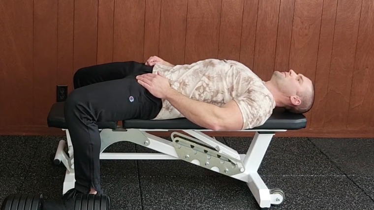 Step 1 - A person properly positioned on the gym bench for a pullover.