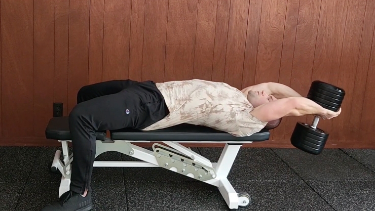 Director Merrick Lincoln plays dumbbell pullovers on a flat bench