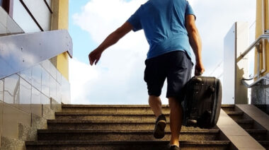 Person walking up stairs carrying luggage