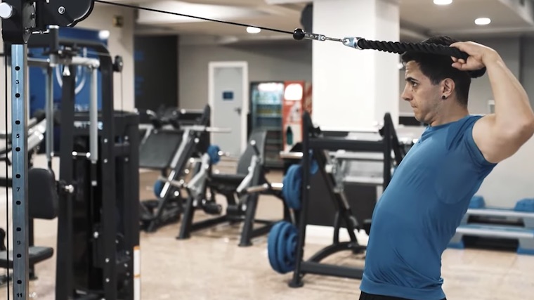 person in gym doing cable shoulder exercise