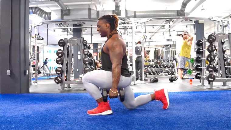 A person kneeling during a dumbbell split squat.