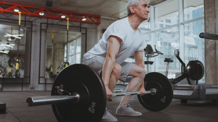 grey-haired lifter performing barbell deadlift