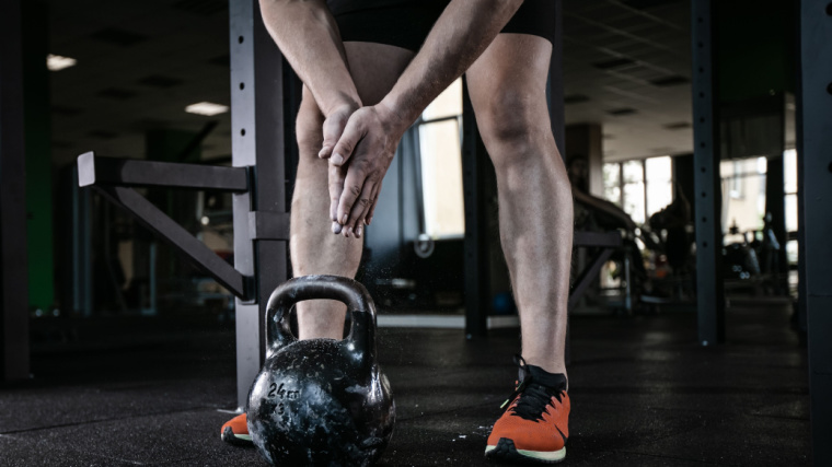 Person in gym preparing to lift kettlebell from the ground
