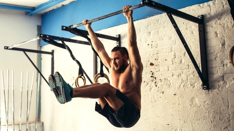 A person hanging from a pull-up bar, gaining upward momentum 