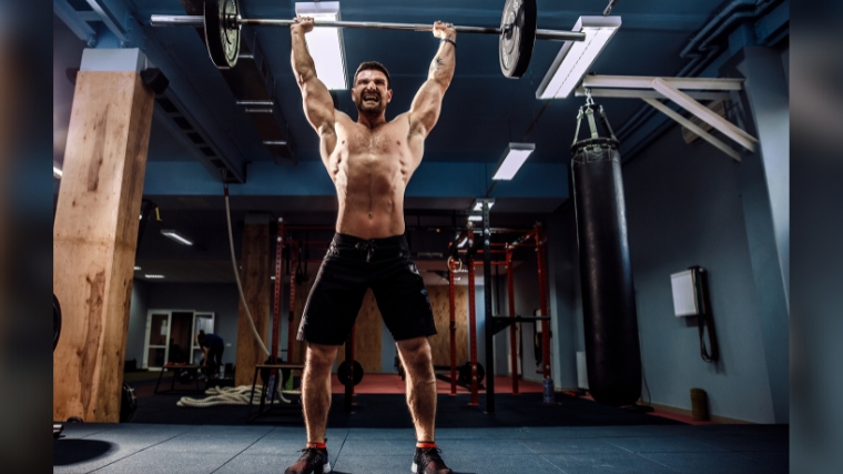 A person holding a barbell up in a complete clean & jerk.