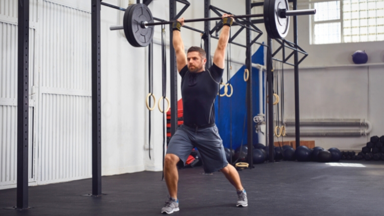 A person jerking the barbell up and splitting during a clean & jerk.