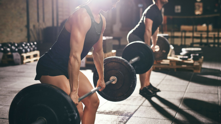 two people in gym lifting barbells from ground