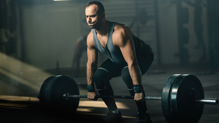 Muscular person in gym doing barbell deadlift