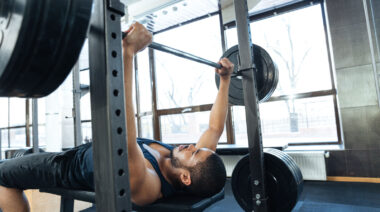 Person in gym performing heavy bench press