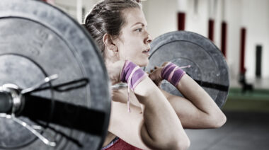Person in gym holding barbell in front squat position