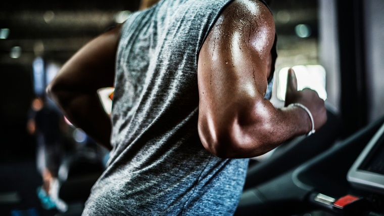 Muscular man sweating in the gym while running on the treadmill