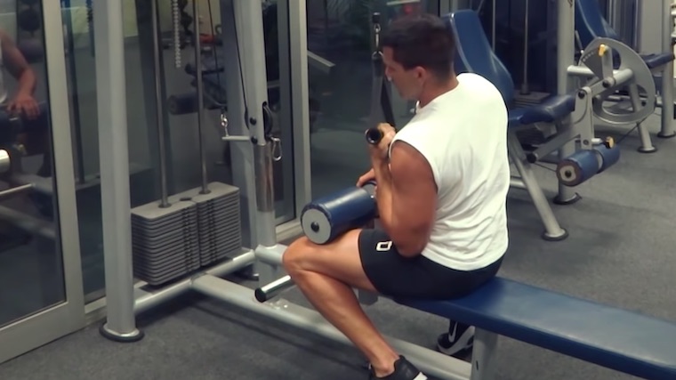 Person in gym doing one-arm back exercise with cable