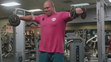 Strongman Mitchell Hooper in gym doing dumbbell shoulder exercise