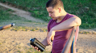 Person outdoors looking at protein drink bottle