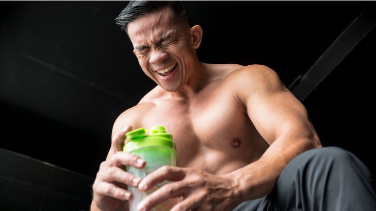 Muscular person in gym drinking pre-workout protein shake