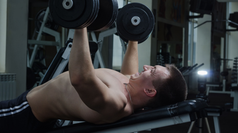 person in gym doing heavy weight incline dumbbell press