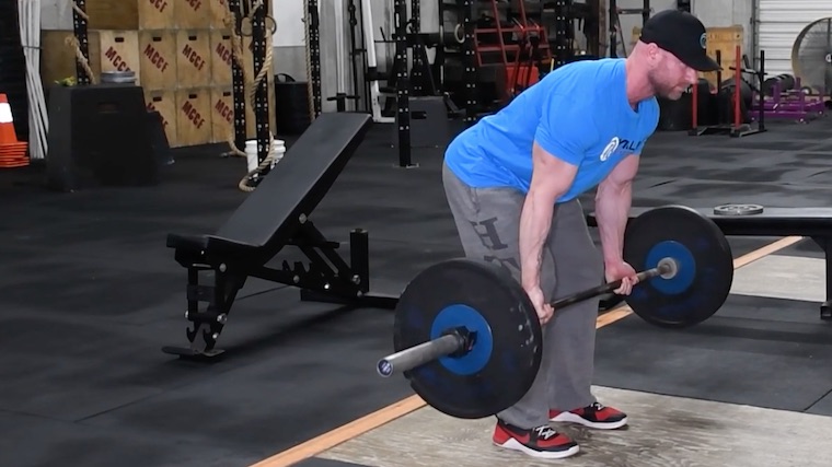 Muscular person in gym doing barbell row