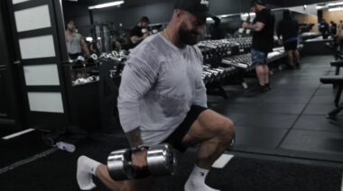Bodybuilder Chris Bumstead in gym doing dumbbell lunge