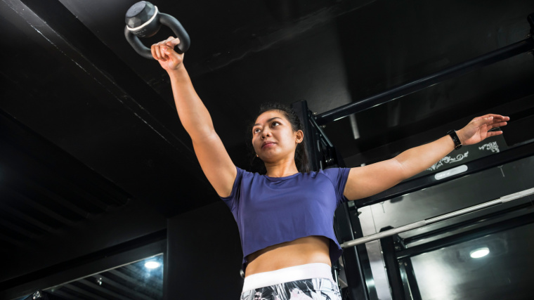 Person in gym doing single-arm kettlebell swing