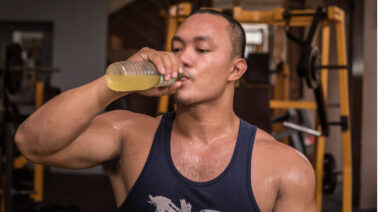 Muscular person drinking protein shake in gym