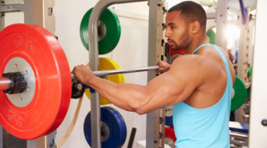 Muscular person in gym grabbing barbell