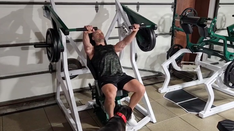 Muscular person in gym doing machine chest press