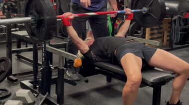 Powerlifter Jen Thompson performing bench press in home gym