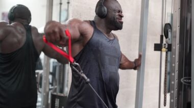 Bodybuilder Samson Dauda in gym performing shoulder exercise
