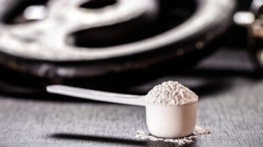 Scoop of creatine in front of weight plates