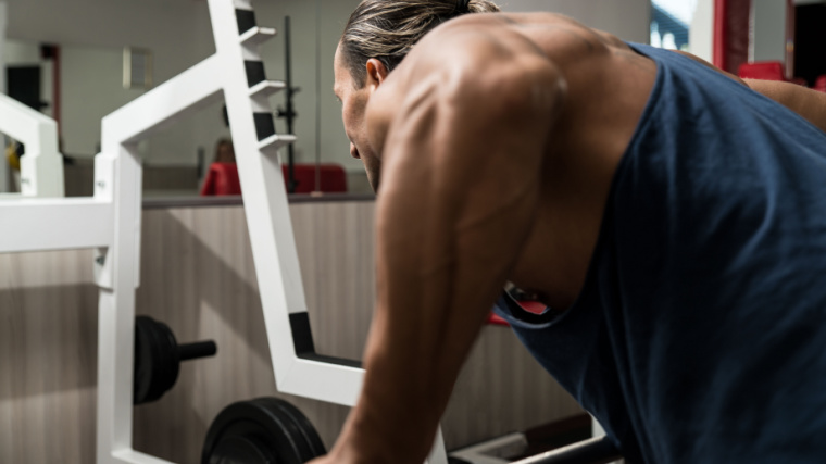 Muscular person in gym performing barbell row