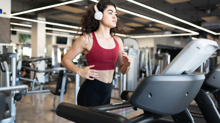 Long-haired person in gym using treadmill