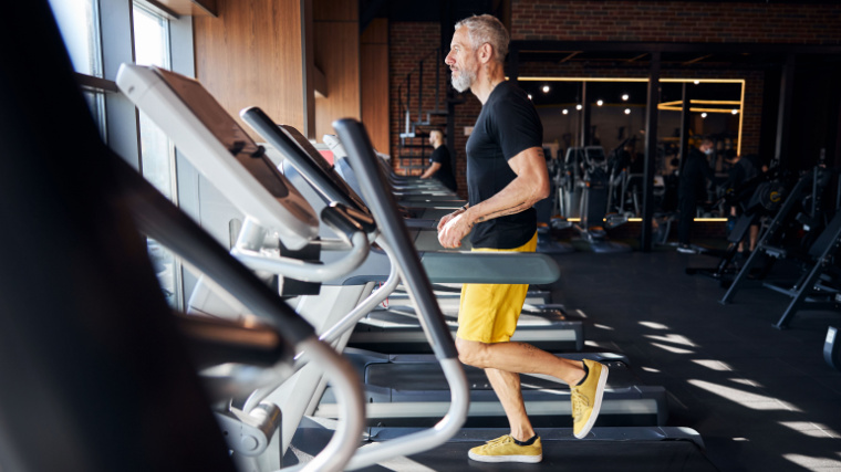 gray-haired person using treadmill in gym