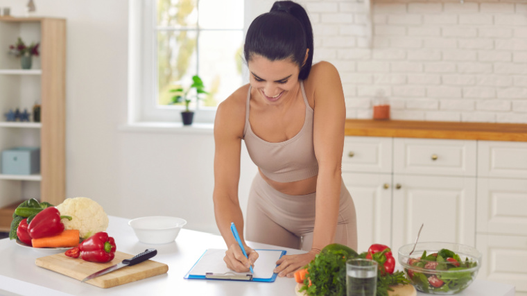 Long-haired person in kitchen writing about food