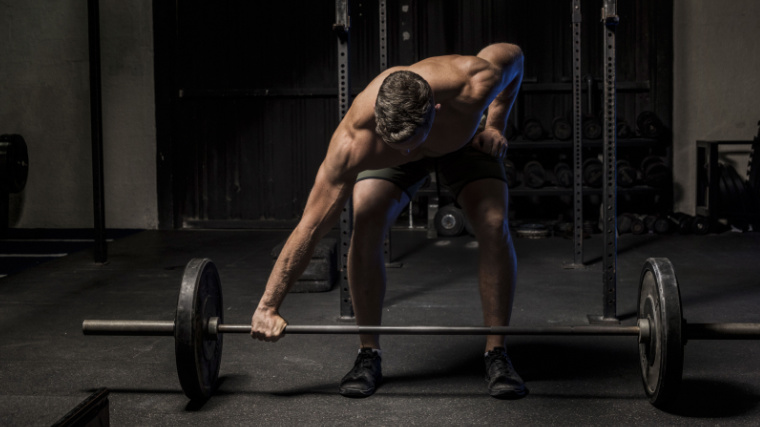 Muscular person in gym preparing to lift barbell