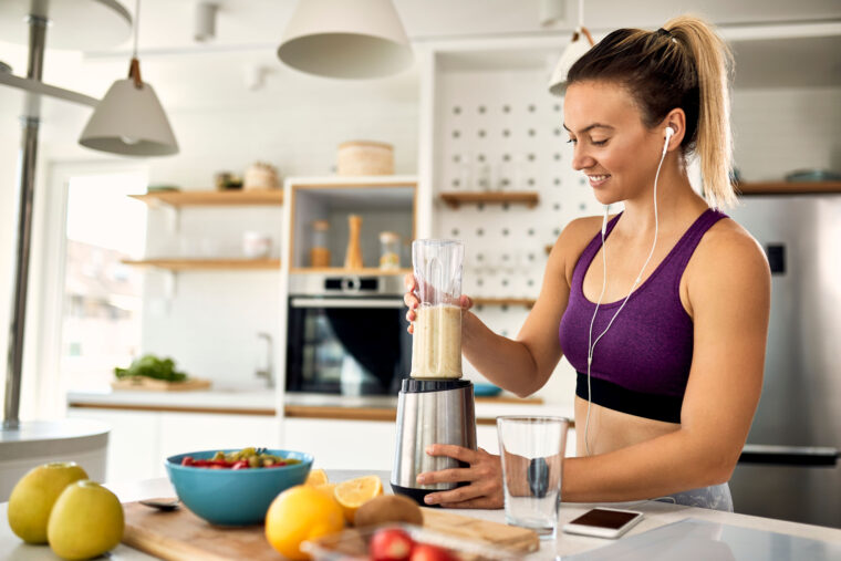 Muscular person in gym making smoothie with blender