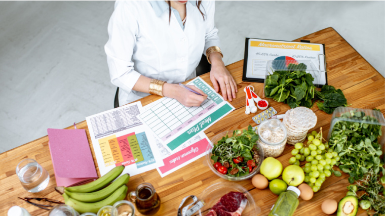 Person sitting near food writing nutrition plan